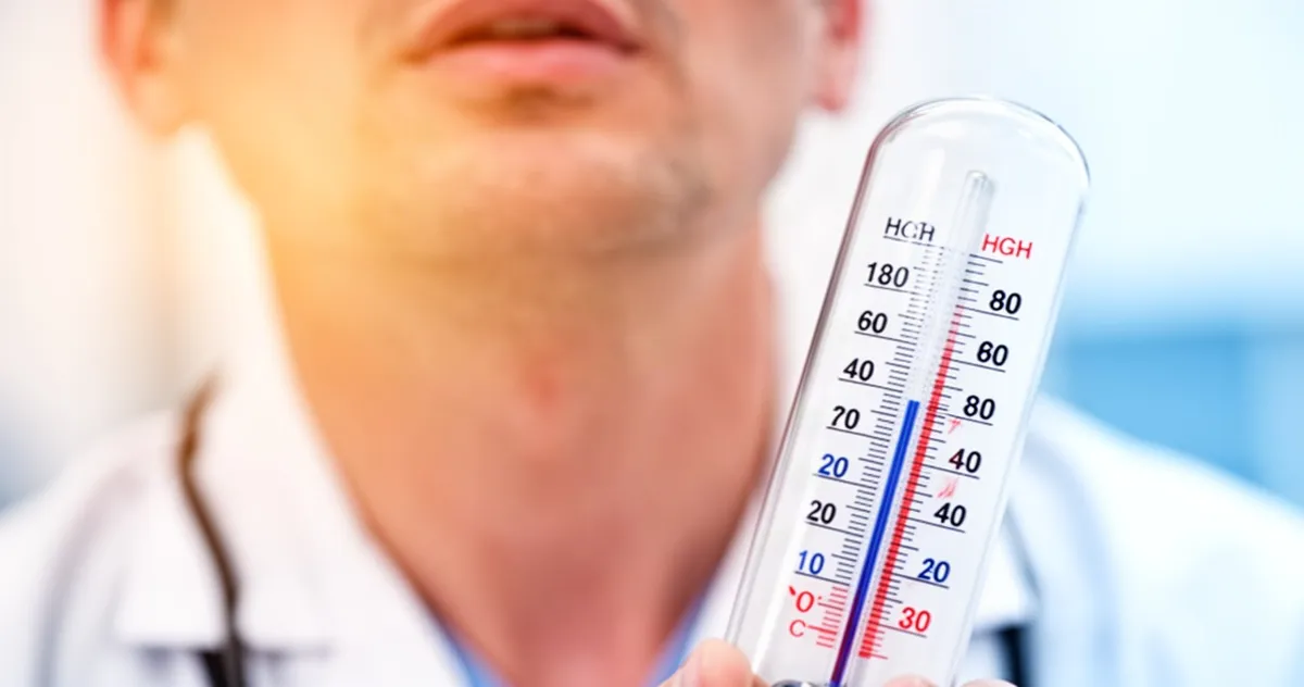 Termometr wskazujący wysoką temperaturę na tle rozmytej szyi pacjenta w gabinecie lekarskim.